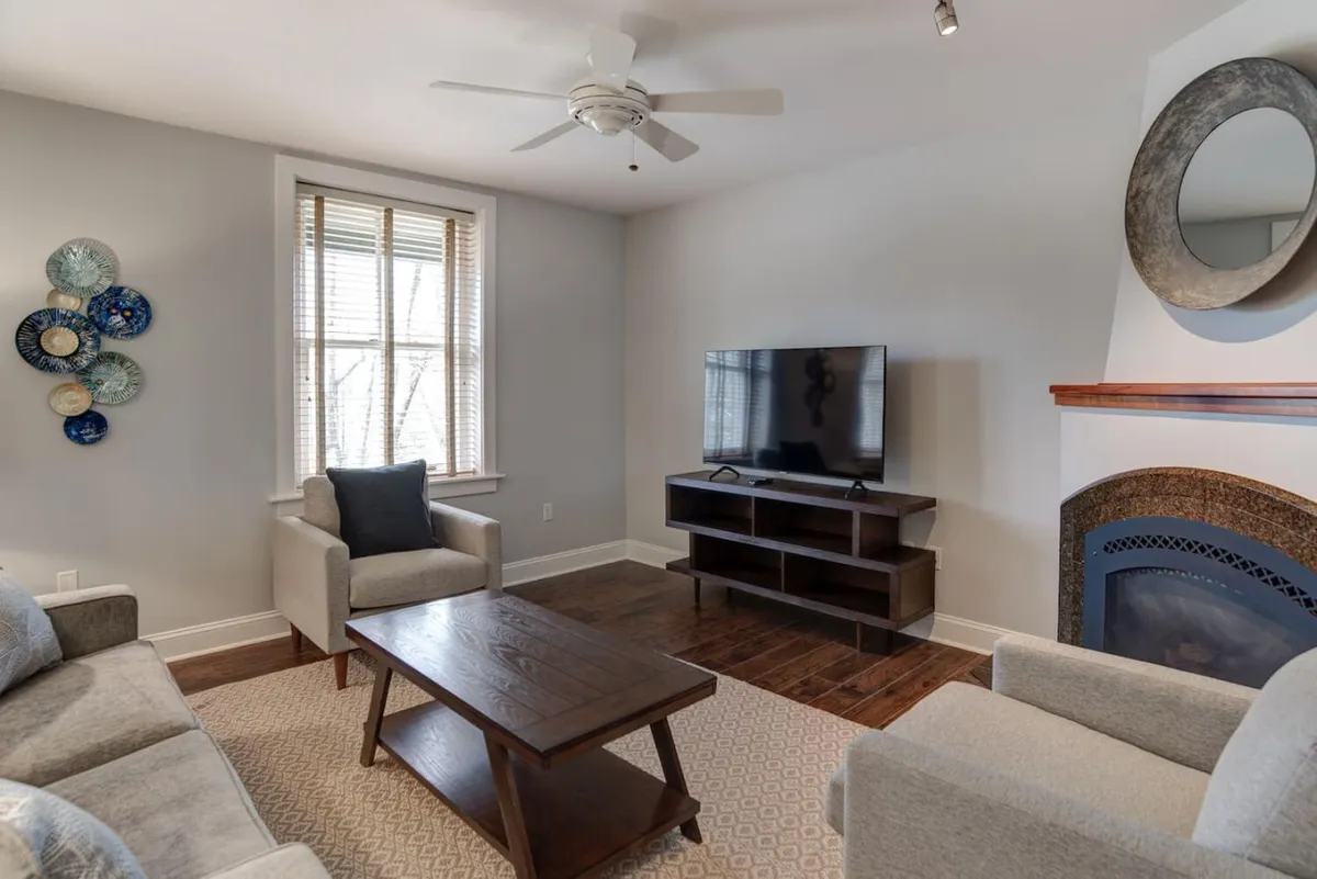 A spacious living area featuring a comfortable sofa, coffee table, television, and fireplace, with decorative plates adding artistic flair. The space is designed for socializing, relaxing, and gathering after a day of exploration.