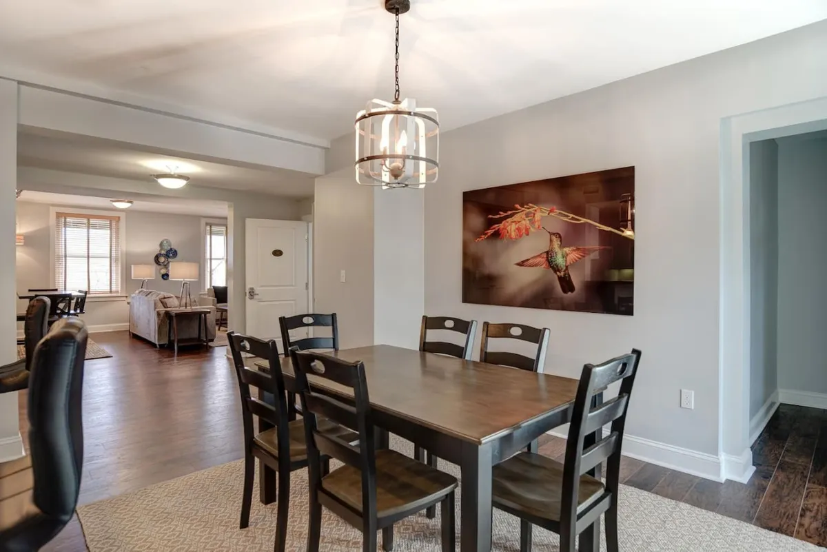 An elegant dining area with a welcoming table beneath a stylish chandelier, accentuated by vibrant hummingbird artwork on the wall. This space radiates warmth, ideal for gatherings, family meals, or memorable celebrations.